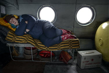 Paramedic Anna sleeps during a long helicopter flight to reach a patient. The vibrations during flights are harmful to the spine and are reduced if by lying in a horizontal position.