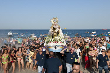 A crowd follows as a statue of the Virgin Mary is carried from a boat in the Mediterranean Sea during a Catholic religious procession.