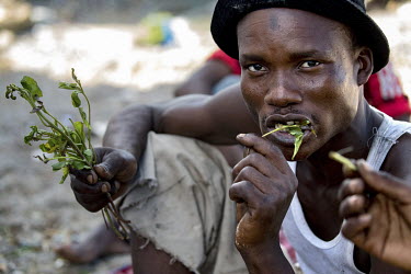 A group of men sit outside chewing khat and smoking.