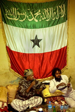 Cheik Abdul Rahim (left) chew khat with a friend while sitting below a flag of Somaliland inside the Cheik Madar Hadrat mosque and tomb.