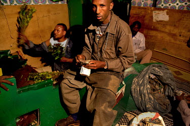 A khat trader counts a wad of banknotes at his stall in a khat nightmarket. The khat is imported by truck from Harrare in Ethiopia and it is a big busness, around GBP 157,000 (USD 200,000) is traded e...