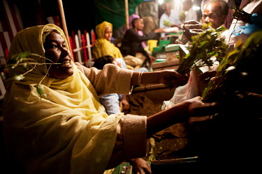 A woman holds a bunch of khat out for sale on her stall in a khat nightmarket. The khat is imported by truck from Harrare in Ethiopia and it is a big busness, around GBP 157,000 (USD 200,000) is trade...