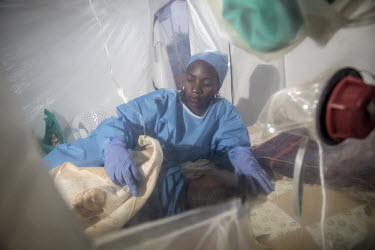 A medical worker who has formerly recovered from Ebola virus and thus can work without the cumbersome personal protective equipment (PPE), treats a patient inside an a plastic Ebola treatment centre,...