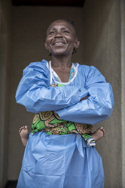 Kavuo Kitambala with her baby strapped on her back in a daycare centre where children whose mothers are being treated for Ebola infection are cared for by Ebola survivors. This reduces the risk of the...