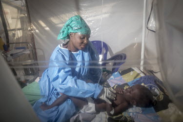 Mwamini Masika, who has recovered from Ebola infection and now works as a carer for children being treated for Ebola, with the child she is looking after. As Masika has survived the infection herself...