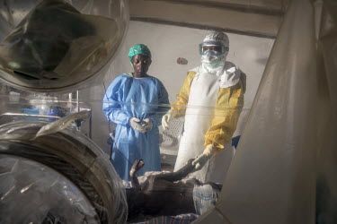 A doctor wearing personal protective equipment (PPE) and a female medical worker, who has recovered from Ebola infection and now works as a carer for children being treated for the virus, with the chi...