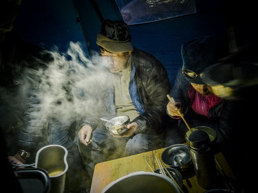 Yang Yong (independent geologist, environmentalist and the director of the Hengduan Mountain Research Institute) and his brother Yang Hongbing cook an evening meal at the camp where the expedition has...