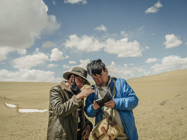 Independent Chinese geologist, explorer and environmental activist, Yang Yong, discusses with a Tibetan herdsman their location on a sattelite map. He says "Although sattelite imaging has documented t...