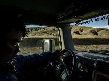 Chinese geologist, explorer and environmental activist, Yang Yong, checks his location on his phone whilst driving to the next location he plans to explore. Throughout this expedition he is exploring...
