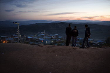 At sunset, a group of youths look down from a hillside towards Lice.
