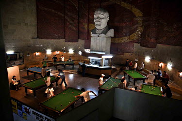 People playing pool (billiards) beneeath the gaze of a huge bust of Lenin in the former Lenin Museum, now a snooker, pool & billiards club.
