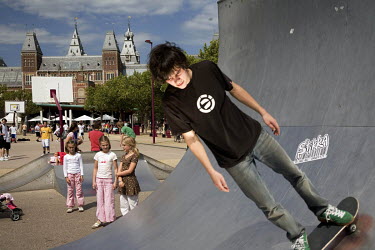 A man rides a skateboard in a section of half pipe in a public park.