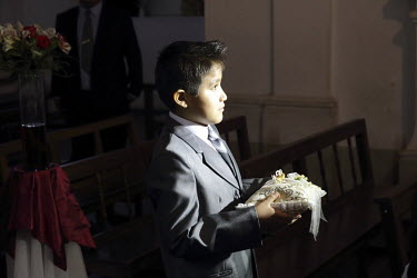 A page boy at the marriage of an Indian couple at the Church of San Lazaro holds a cushion on which sits the couple's wedding rings.
