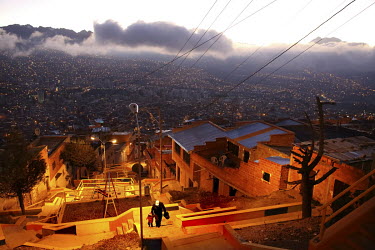 A man and a child walk up a staircase high up on a hillside in La Paz where suburbs reach 4100m and the city centre is at 3100m.