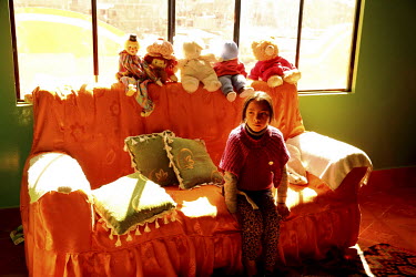 A girl sits on a sofa in her father's apartment that is in a 'Cholet-style' building. These buildings represent the new Indian architecture. The majority were built by the architect of Aymara Indian h...