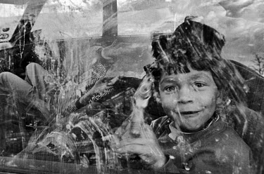 A Roma boy plays with a toy gun inside a car.