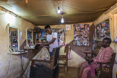 Oladele Hammed cutting hair in his barber's shop in the rural community of Gbamu Gbamu where the power is supplied from the Rubitec renewable power station.