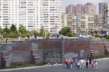 Children play beside a wall in a residential district, where new blocks of flats are being constructed.