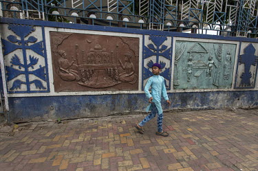 A boy walks past a decorative relief on a wall in the Muslim neighbourhood around the Nakhoda Mosque.