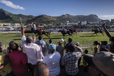 Racegoers cheer on their horses at the weekly horse-racing meeting in the Champs de Mars arena.