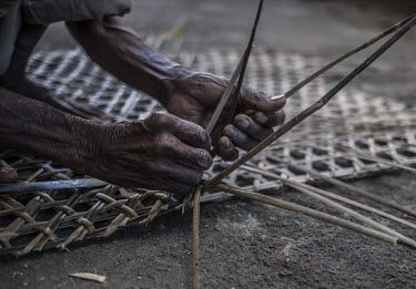Ramesh Rambaran (60) weaves a traditional bamboo fishing trap outside his home in the fishing village of Poudre d'Or.