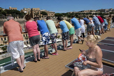 Passengers look out over Valetta from a deck onboard the MSC Lirica a cruise ship, belonging to the Mediterranean Shipping Company, as it heads towards the cruise terminal in the Grand Harbour.