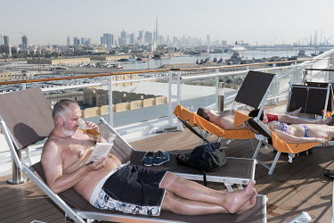 Passengers sunbathe and drink beer on the upper deck of the MSC Musica during a six day cruise through the Persian Gulf and the Gulf of Oman, from Muscat to Abu Dhabi. The Dubai skyline is visible on...