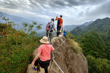 Hikers pose for photos on a precipitous ridge along the Wuliaojian Mountain hiking trail.