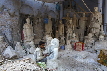 A stone mason/sculptor carving images of famous people.