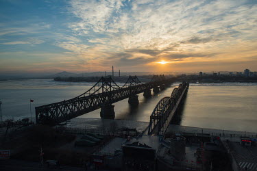 The China - North Korea Friendship Bridge and The Yalu River Broken Bridge (R) seen from a hotel window during the sunset in winter. The bridges connect Dandong in China with Sinuiju.