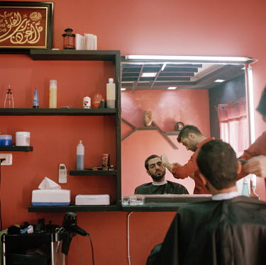 Mahmoud (25) at the barber for his weekly shave. He studied Business Administration in Turkey but left before finishing. Now back home he opened a cafe and also started the website ''let's have fun in...