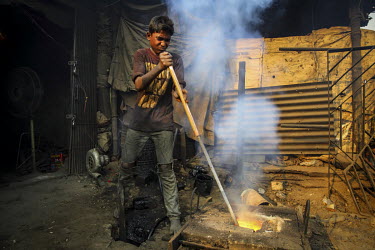 A child labourer, with no safety equipment, smelting metal for casting ship's propellors.