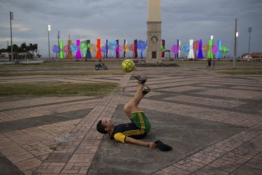 Jazel Reyes (25) practices freestyle football (soccer) on the Plaza John Paul II, with the 'Trees of Life' on the Malecon in the background.