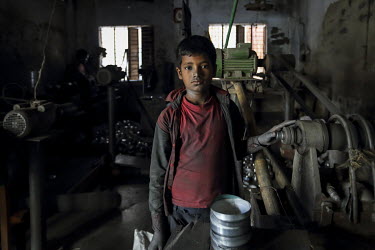 A child working in a factory making metal cooking pots. It is common in practice for the children of poor parents to work in various hazardous and labour-intensive workplaces to support their families...