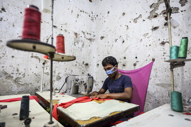 A worker sews t-shirts in a factory where he works a 12 hour day and is paid less than GBP 20 per month.