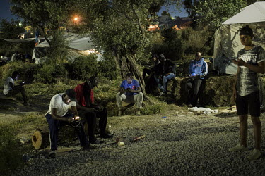 People using mobile phones in an informal extension of Moria camp known as Olive Grove. The awful conditions at Olive Grove and arbitrary administrative situations have had a dramatic impact on their...