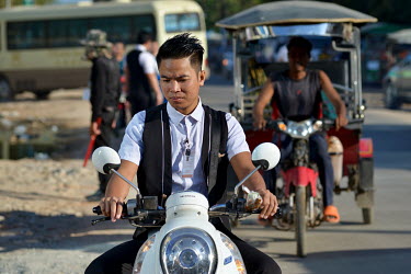 A youth who has a job as a card dealer at a casino arrives on his new scooter to begin a shift.