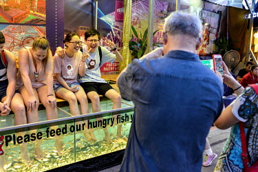 Western and mainland Chinese tourists having their feet 'massaged' by tiny fish in the night market.