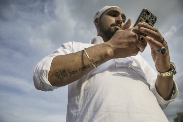 A man checks his smartphone as a crowd of around 12,000 Sikh migrants and their Italian born children, representing the Sikh community of the Po Valley and beyond, parade through the town's streets, p...