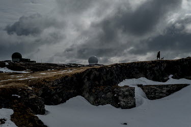 A woman walks her dog near two of the town's three radar stations. The station to the right is the Globus II intelligence gathering radar.