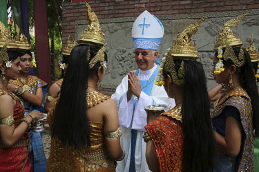 A bishop greetsa group of folk dancers wearing traditional costumes outside a Catholic church on the feast day of the Assumption of Mary.