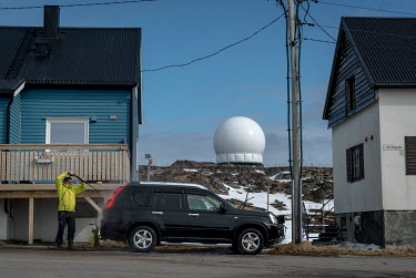 a man washes his car in the shadow of the Globus II intelligence gathering radar.