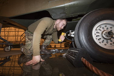 Engineer, Jack Braithwaite, examines a British Merlin helicopter in a heated hangar in the Arctic during Joint Helicopter Command training.~~845 Naval Air Squadron is a squadron of the Royal Navy's Fl...