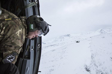 An air crew member looks out the door of a British Merlin helicopter during exercise Clockwork in the Arctic.  845 Naval Air Squadron is a squadron of the Royal Navy's Fleet Air Arm. Part of the Com...