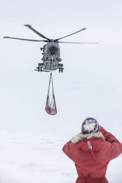 Volunteer Kaisa-Wenche Vivisdatter watching British soldiers on a helicopter mission to transport firewood to a remote Norwegian cabin, the newly built Vouma cabin in the Dividalen National Park, a pa...