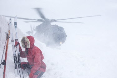 Volunteer Kaisa-Wenche Vivisdatter holding on to her skies as British soldiers arrive by helicopter to deliver firewood to a remote Norwegian cabin, the newly built Vouma cabin in the Dividalen Nation...