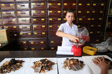 A woman dispenses Chinese medicine at a herbal pharmacy.