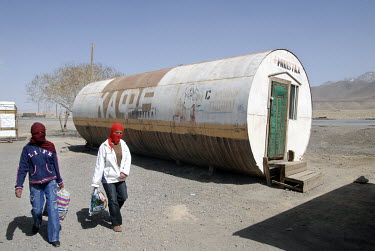 Two girls walk past a cafe set up in a former metal storage tanker.