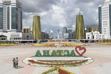 An 'I love Astana' sign, in a square near the presidential palace. In the background among many modernist buildings are the Golden Towers.