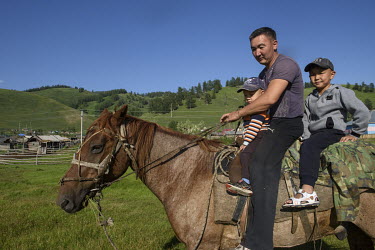 A man rides a horse with his young children.
